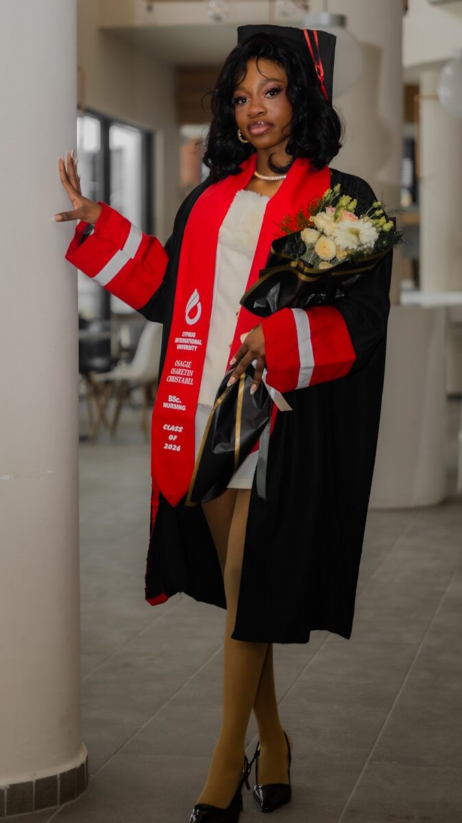 Young woman in graduation gown holding flowers and bouquet